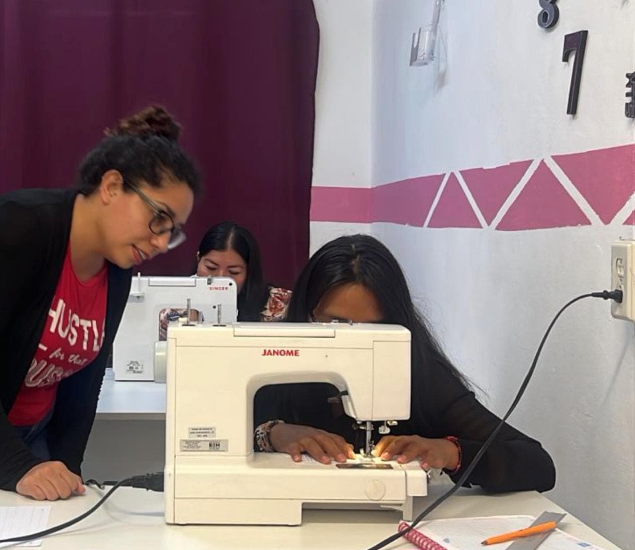 Maestra acompañando a alumnas en sus primeras puntadas con máquina Janome