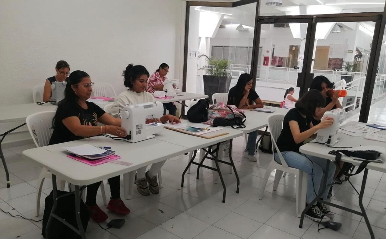 Aula con alumnas trabajando simultáneamente en sus máquinas de coser