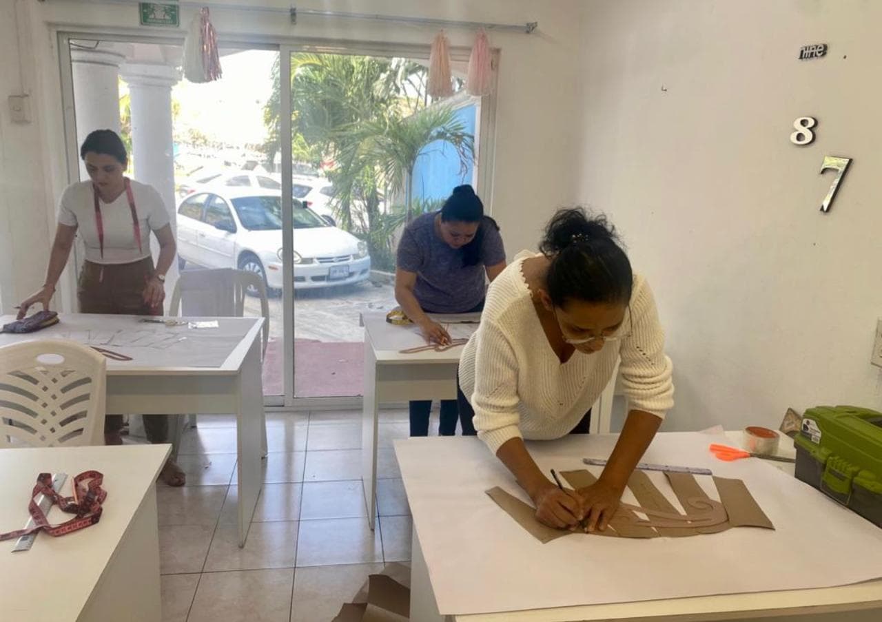 Alumnas trazando y cortando moldes en papel sobre las mesas de trabajo