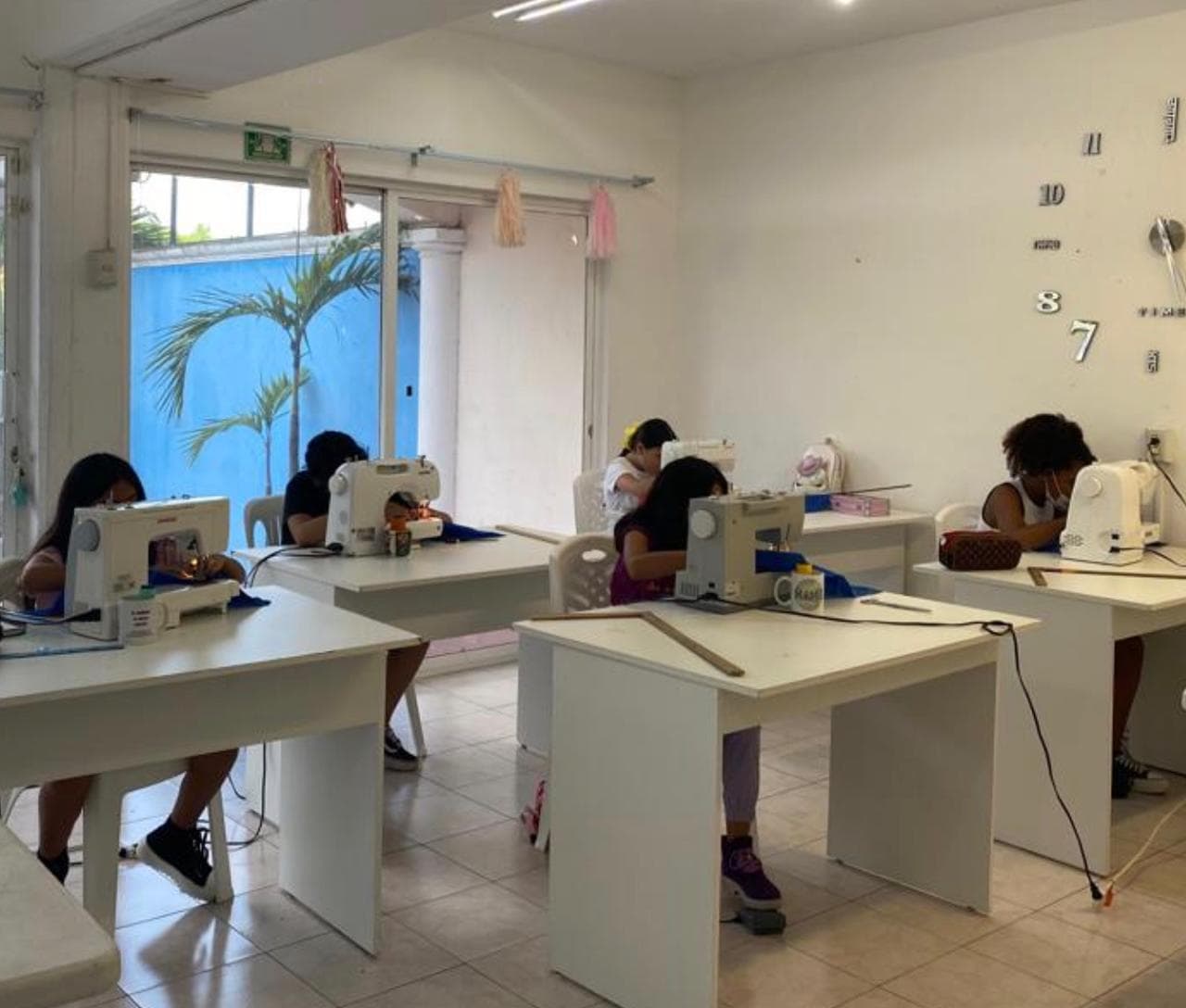 Clase práctica con alumnas confeccionando prendas en máquinas Singer