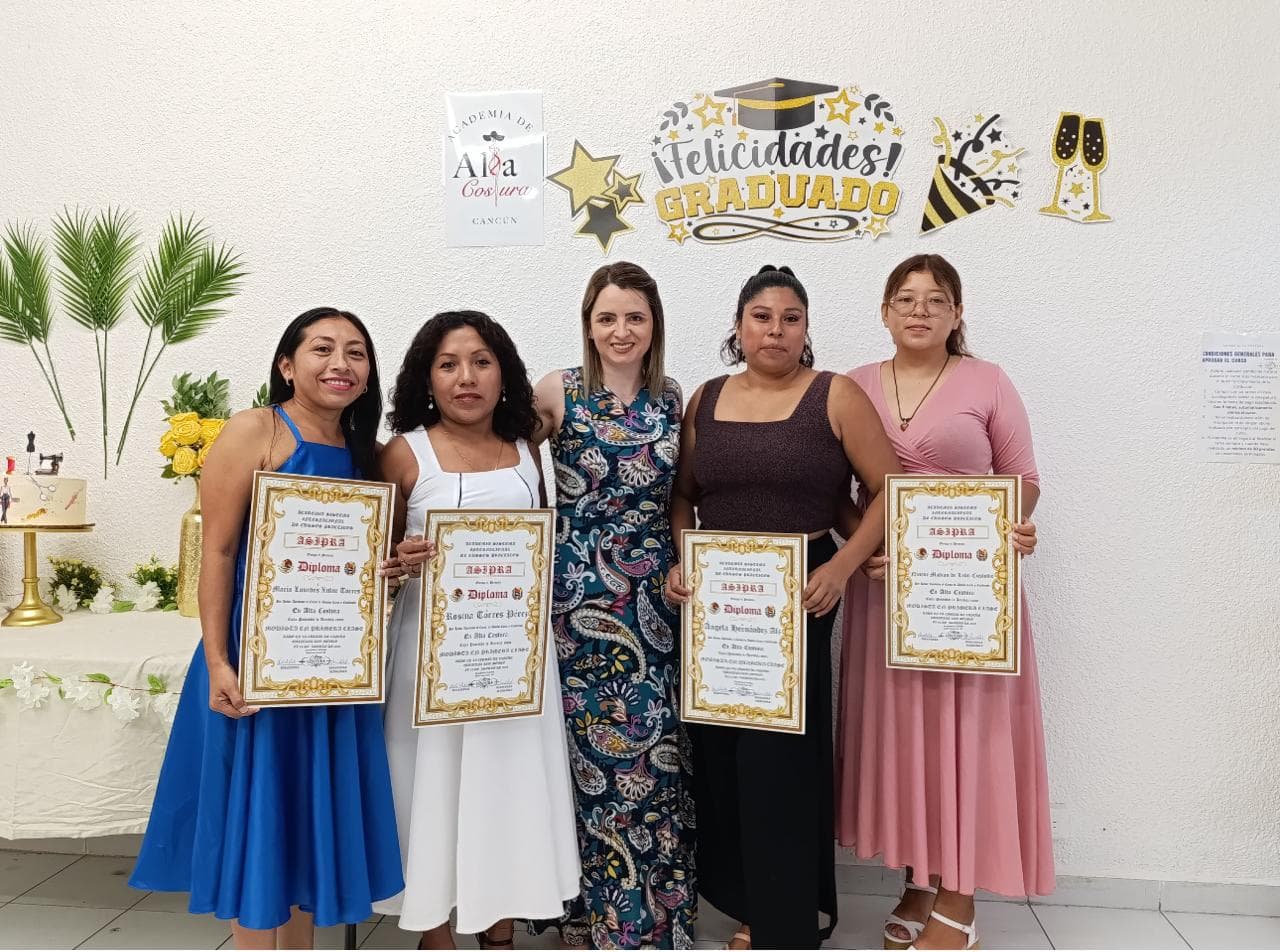 Grupo de cinco alumnas posando con sus diplomas de graduación