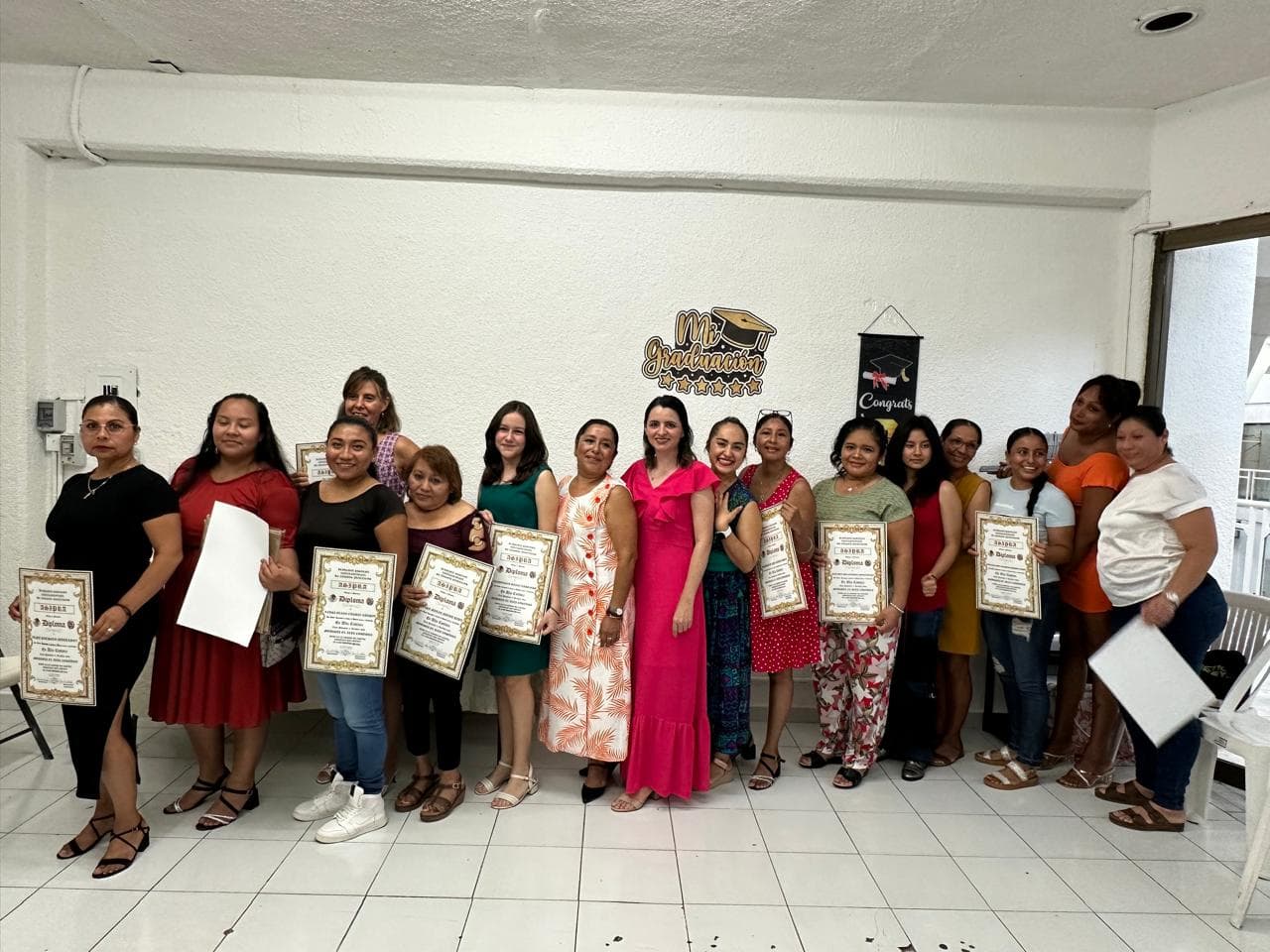 Grupo numeroso de graduadas mostrando sus diplomas oficiales