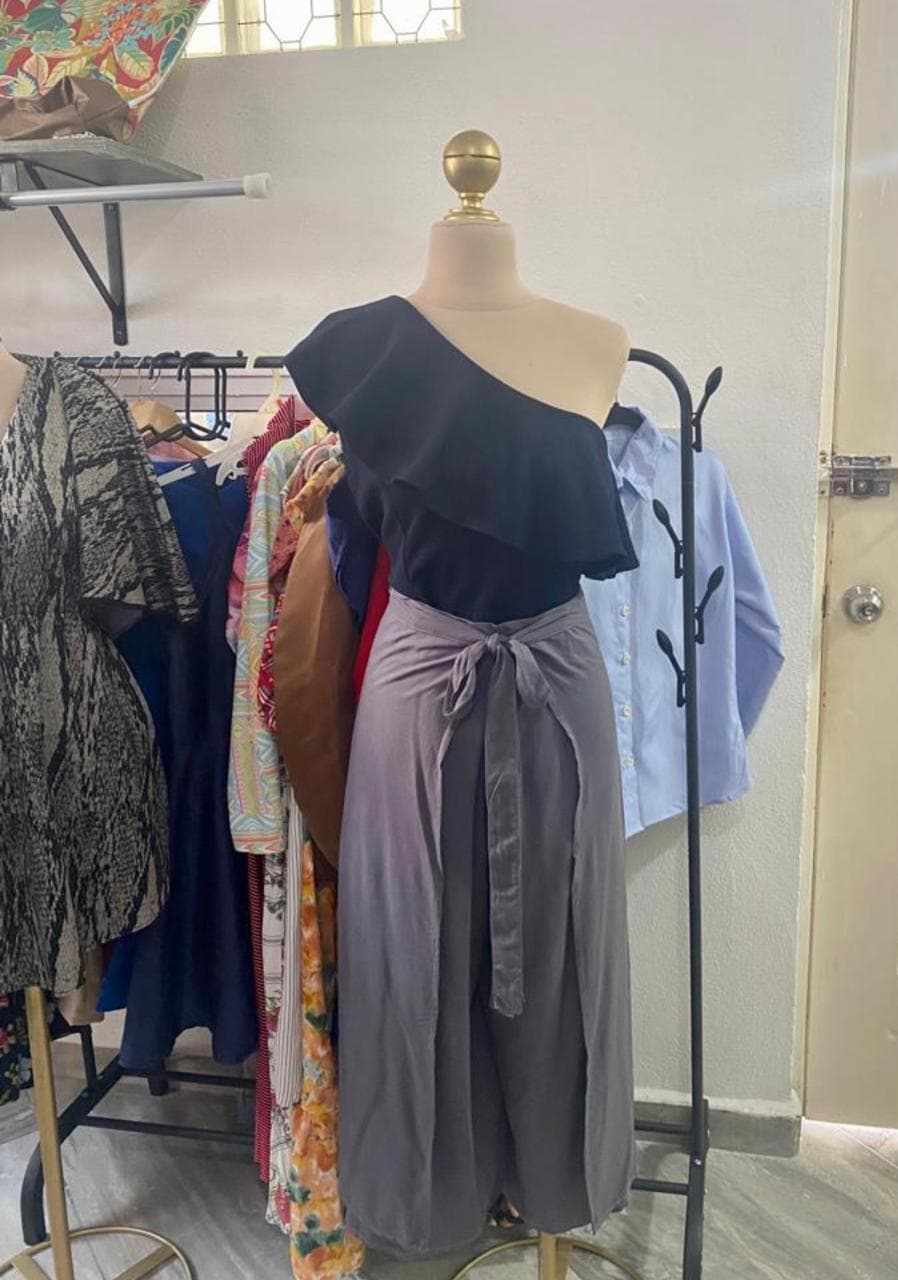 Conjunto de blusa asimétrica negra y falda gris cruzada en maniquí